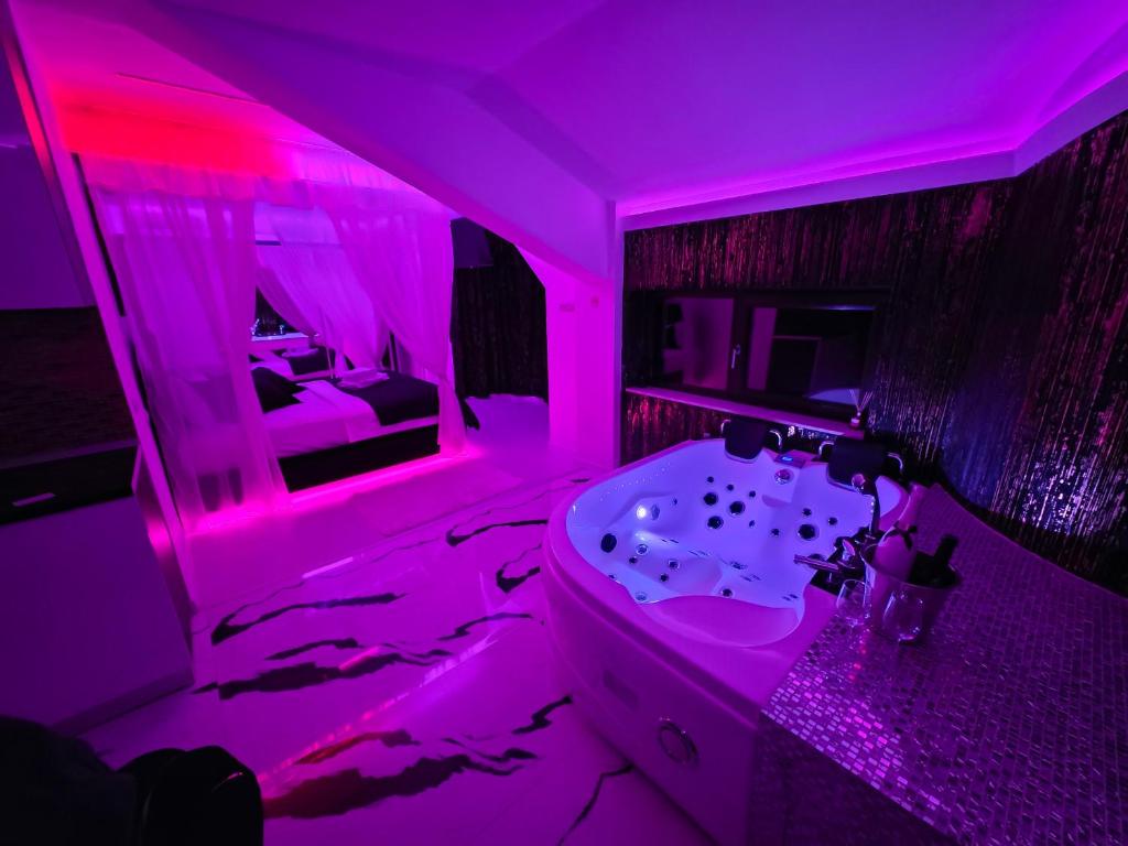 a bathroom with pink lighting and a sink and a tub at Luxury Central Studio in Craiova