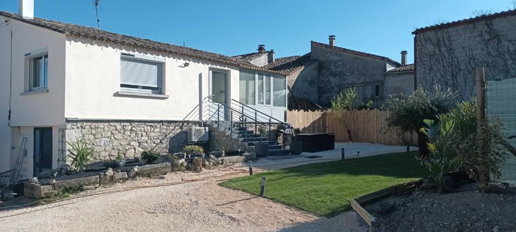 a white house with a fence and a yard at Gîte L'Olivier - Piscine partagée in Lagorce