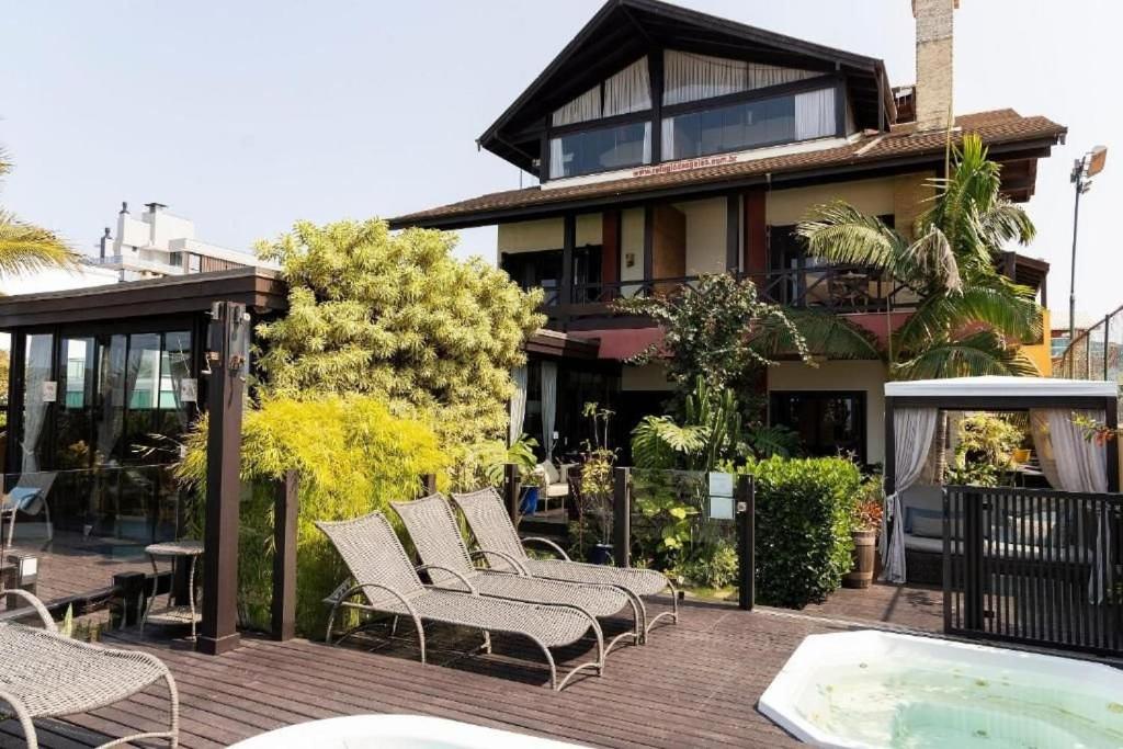 a group of chairs sitting on a deck next to a house at Refúgio das Galés Mariscal in Bombinhas