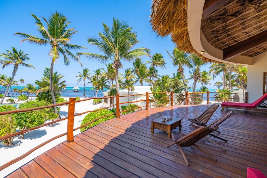 a deck with two chairs and a table on the beach at La Perla del Caribe - Villa Opal in San Pedro
