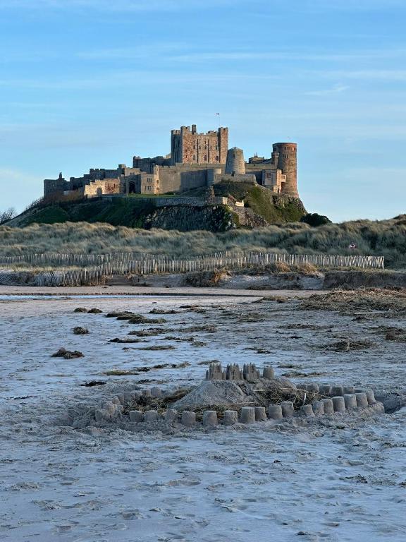 a castle sitting on top of a sandy beach at Brada View - Bamburgh, Northumberland in Bamburgh