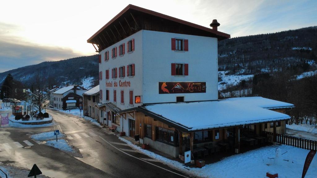 a large building with snow on the top of it at Hôtel du Centre - Restaurant Lelex'ir in Lélex