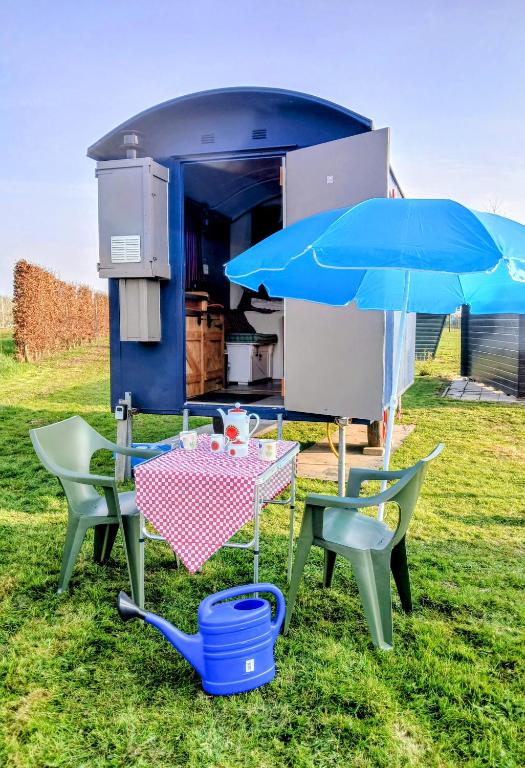 a picnic table and chairs with a blue umbrella at Pipowagen Eldikse Blauwe in Lienden