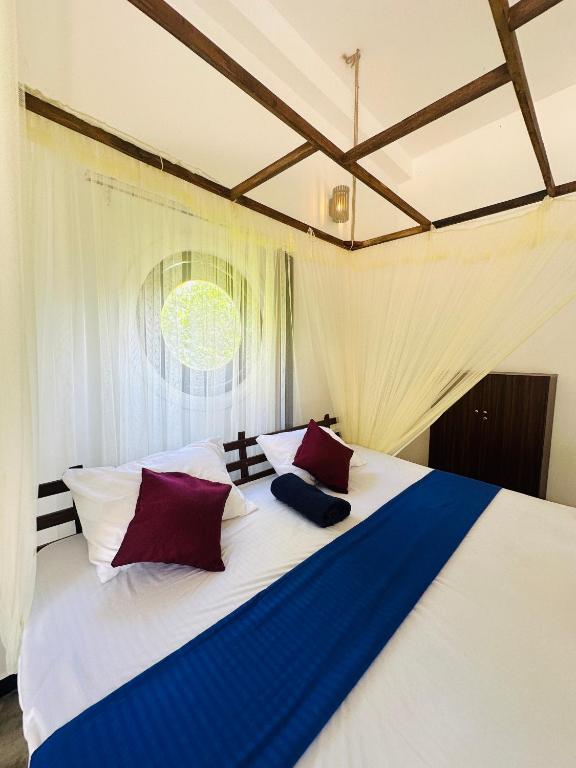 a bedroom with a large white bed with red and blue pillows at Dacha Retreat in Midigama East
