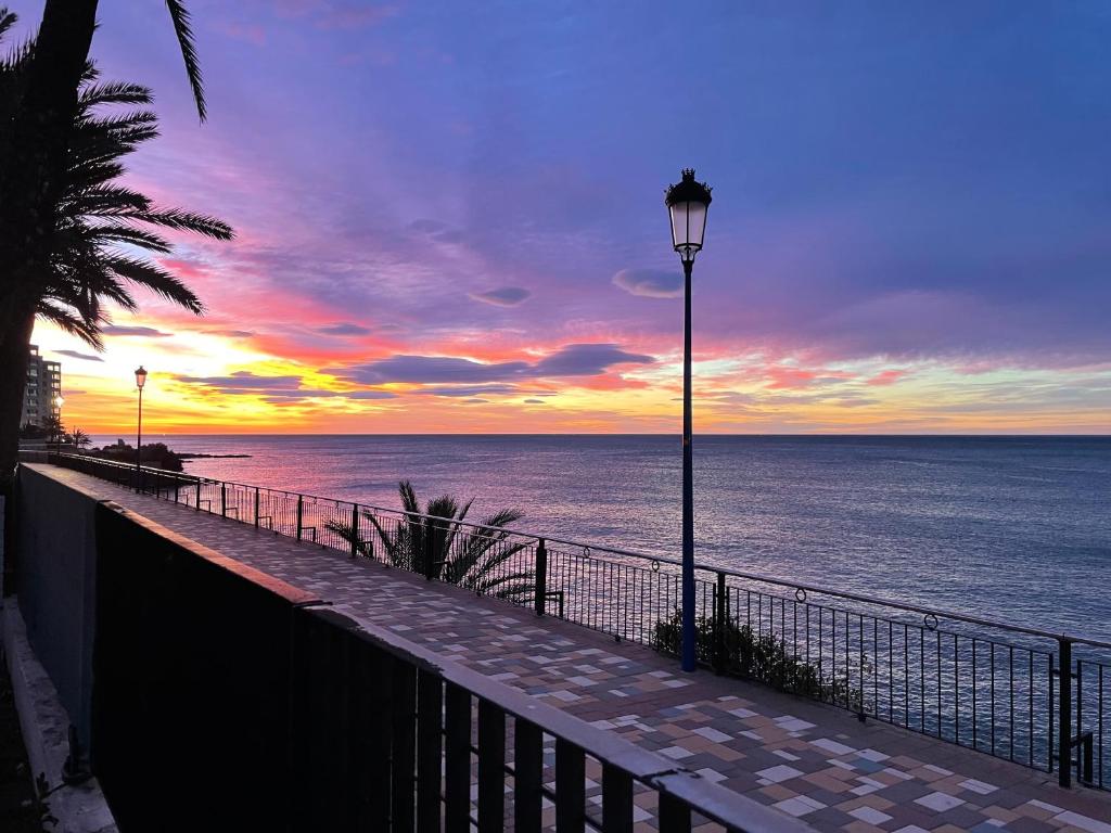 a street light next to the ocean with a sunset at Ferienhaus direkt am Strand mit Terrasse und Meerblick in Torrevieja in Punta Prima