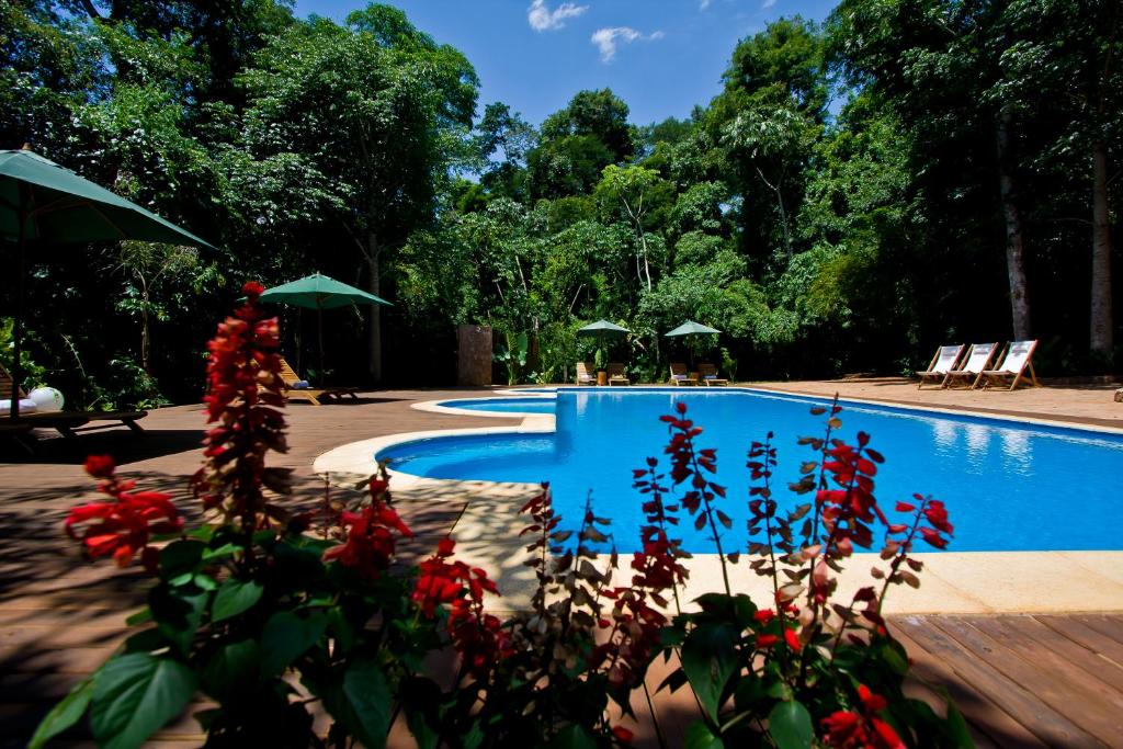 a swimming pool with red flowers in front of it at Tierra Guaraní Lodge in Puerto Iguazú