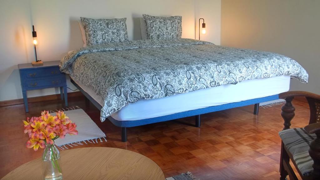 a bedroom with a bed and a vase of flowers on a table at Faial Cottage in Cedros