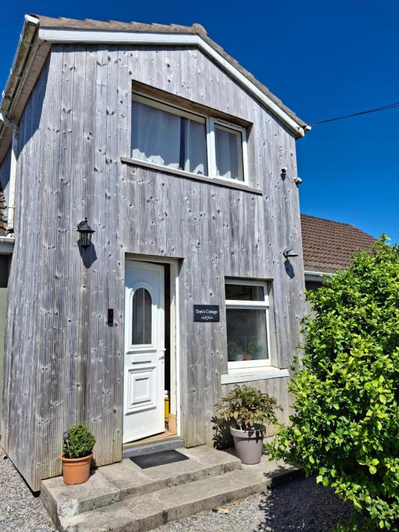 a gray building with a white door and windows at Tom's Alpaca Cottage in Mooncoin