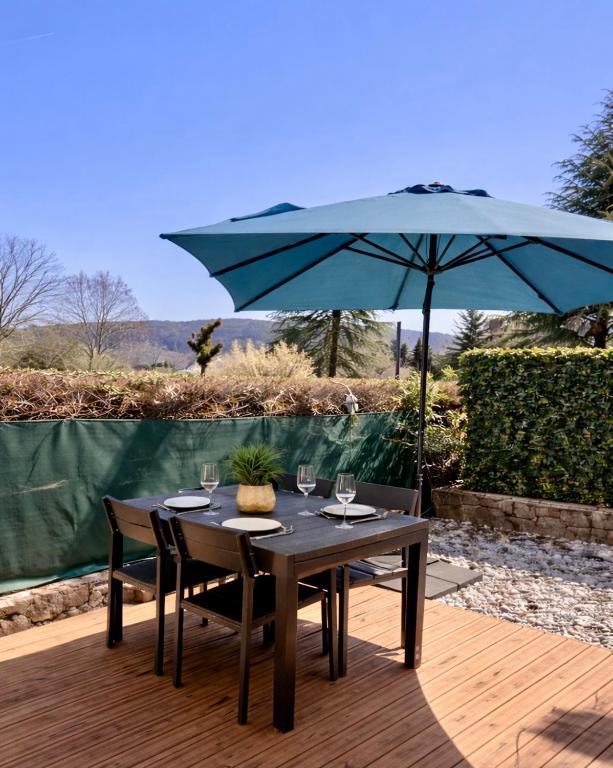 a table with a blue umbrella on a wooden deck at Le Paradis' c'est ici in Gréoux-les-Bains