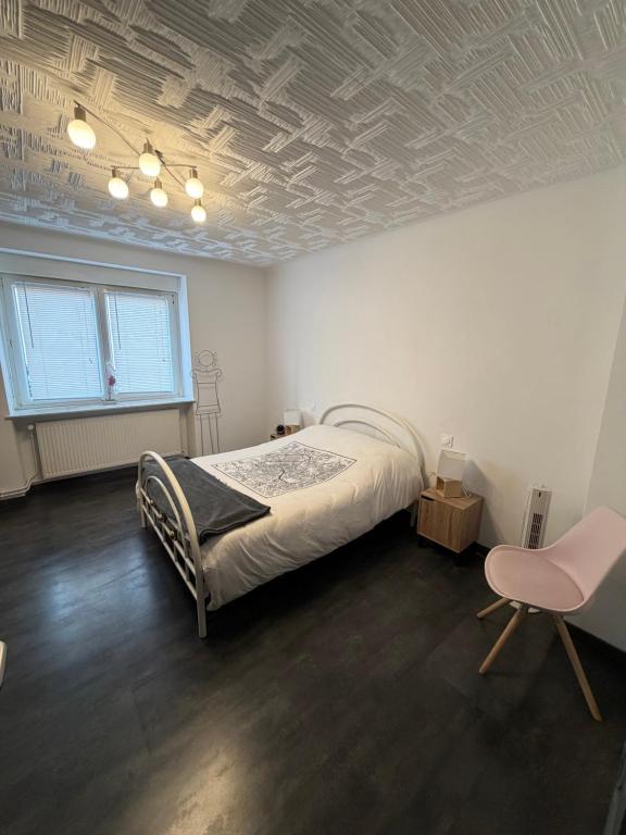 a bedroom with a bed and a chair in it at La Parenthèse coté Saar in Wittring