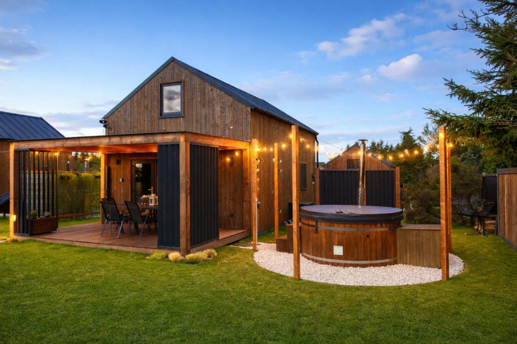a wooden house with a hot tub in the yard at Marine house-Nowoczesna stodoła nad morzem,duży ogród,prywatny hot tub in Kołczewo
