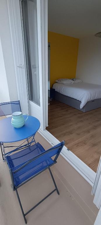 a blue chair and a table in a room with a bed at Le balcon du square in Rennes