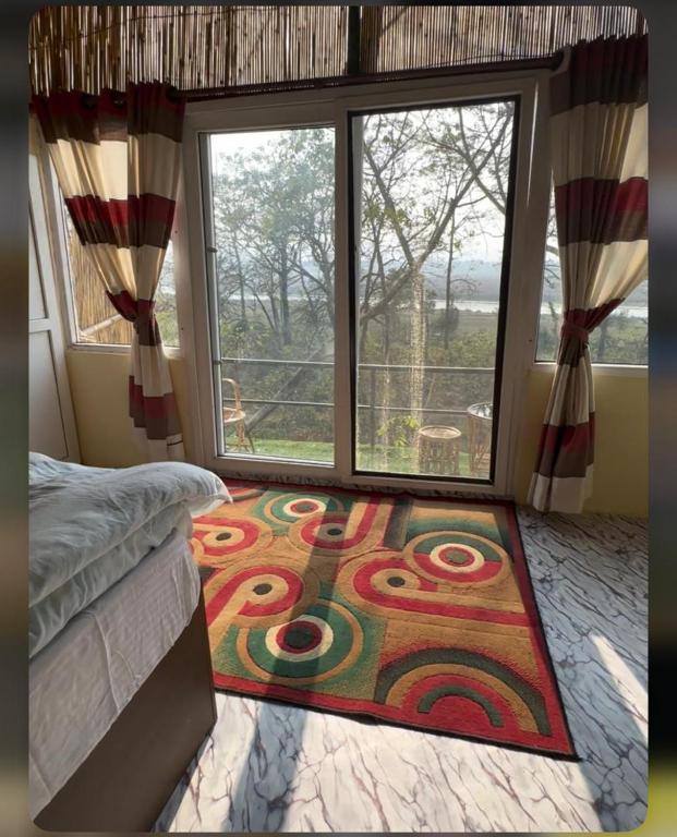 a bedroom with a large window and a rug at Jungle Nirvana Retreat in Meghauli