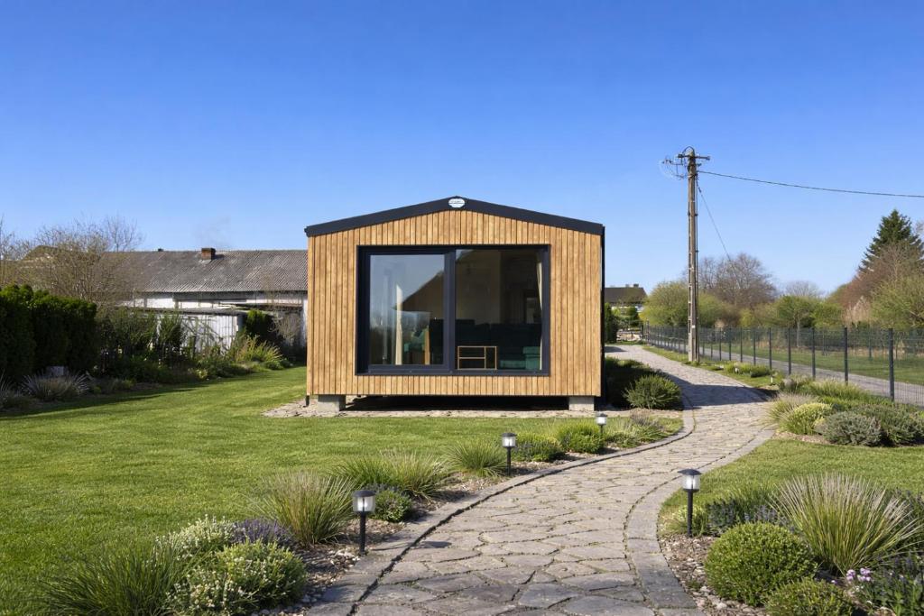 a small house with a large window in a yard at EkoOazy nad Jeziorem in Firlej