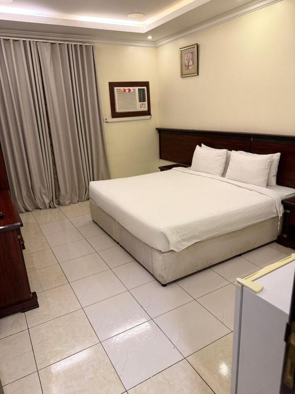 a bedroom with a large bed with white sheets at واحة الاحساء للشقق المخدومة in Al Hofuf