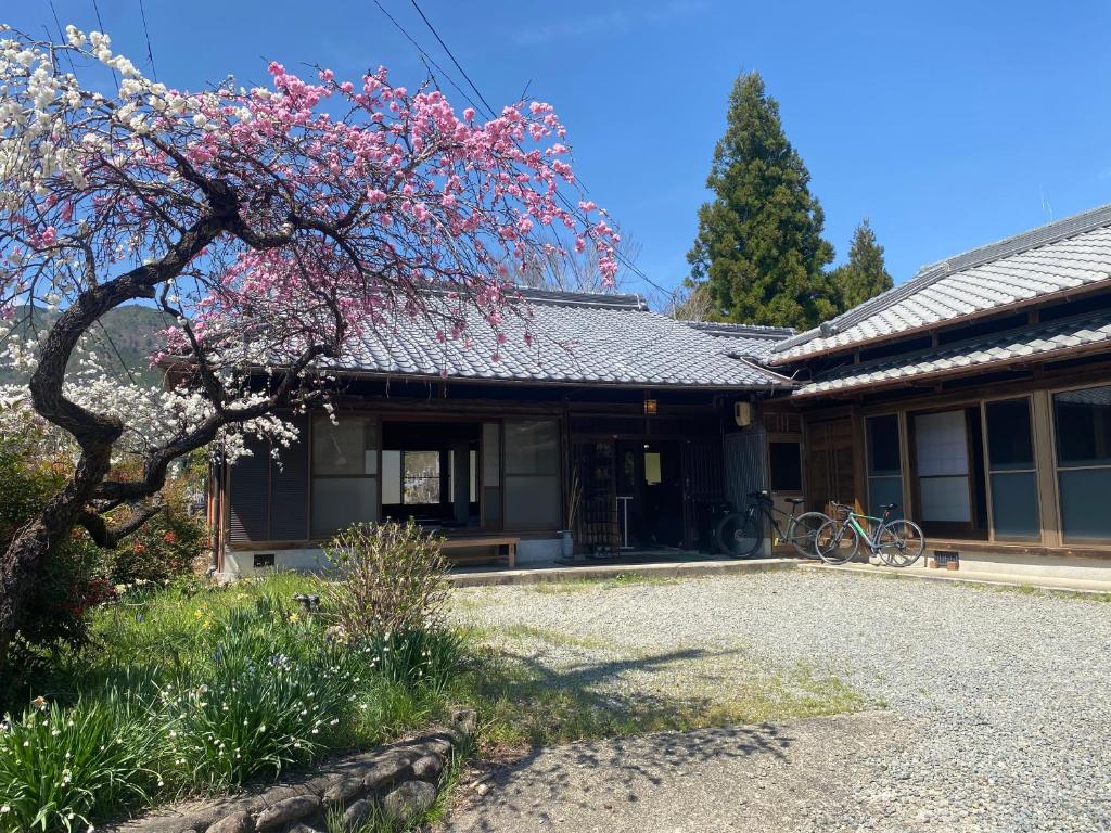 a house with a flowering tree in front of it at Hostel Kumano Kodo in Tanabe