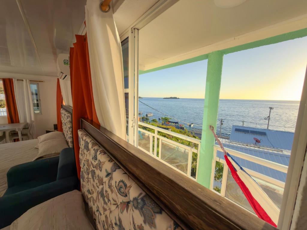 a bedroom with a view of the ocean from a window at Posada Three Cay Suites in Providencia
