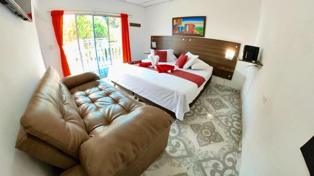 a bedroom with a bed and a leather couch at Hotel terranova in Melgar