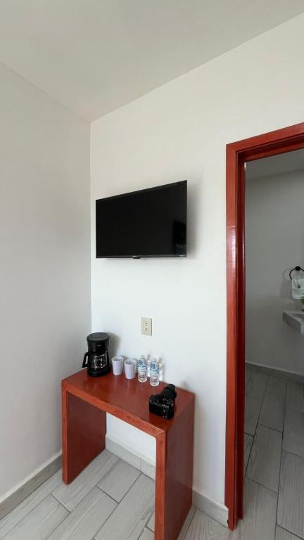 a room with a table with a television on a wall at Hotel Las Arenitas in Mazatlán