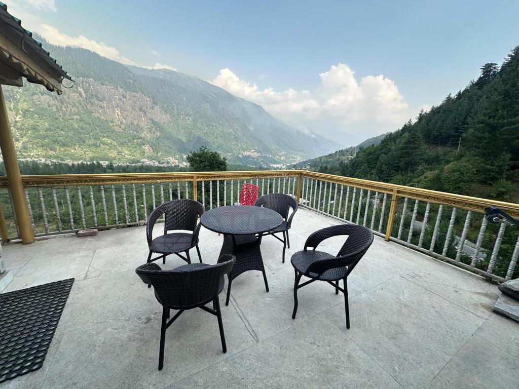 a patio with four chairs and a table on a balcony at Hotel sno cottage in Vashisht