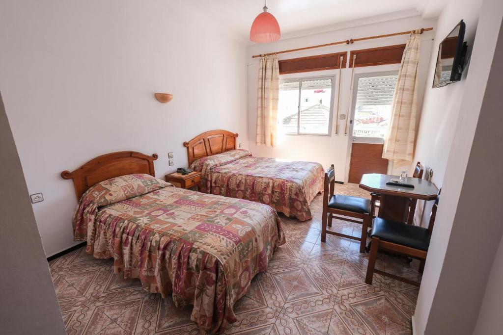 a hotel room with two beds and a table at Hotel Fnidaq in Fnidek