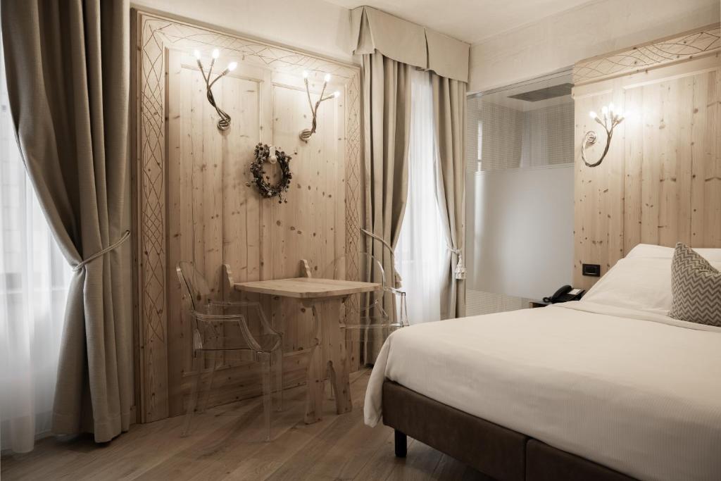 a bedroom with a bed and a wall with antlers at Hotel Orso Grigio in Cavalese
