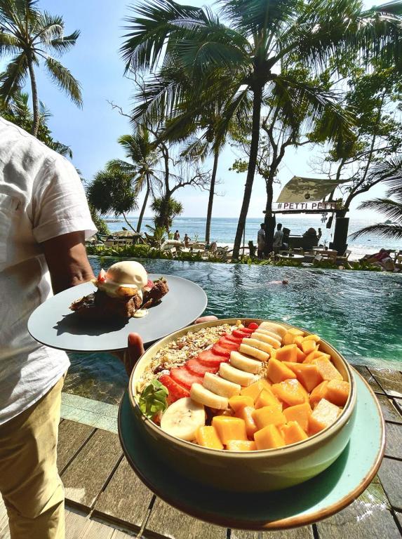 a tray of food on a table next to a pool at Petti Petti Beach Club- Mirissa in Mirissa