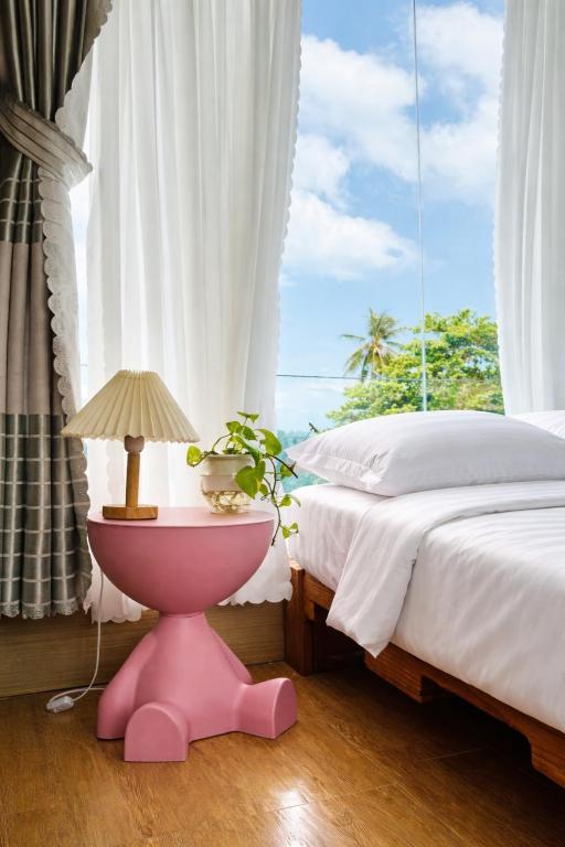 a bedroom with a pink table and a bed and a window at Home Sake Hòn Sơn in Lai Sơn