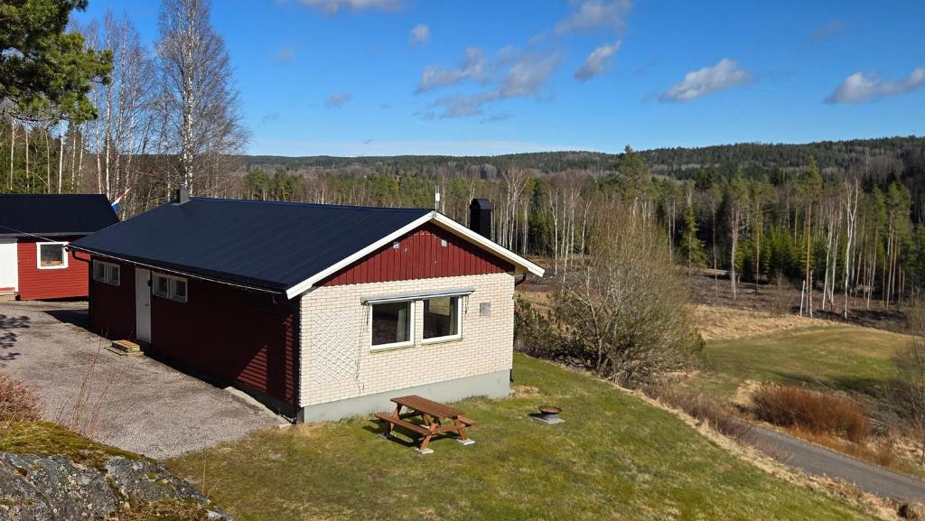 a small house with a black roof on a field at Lagom huset in Årjäng