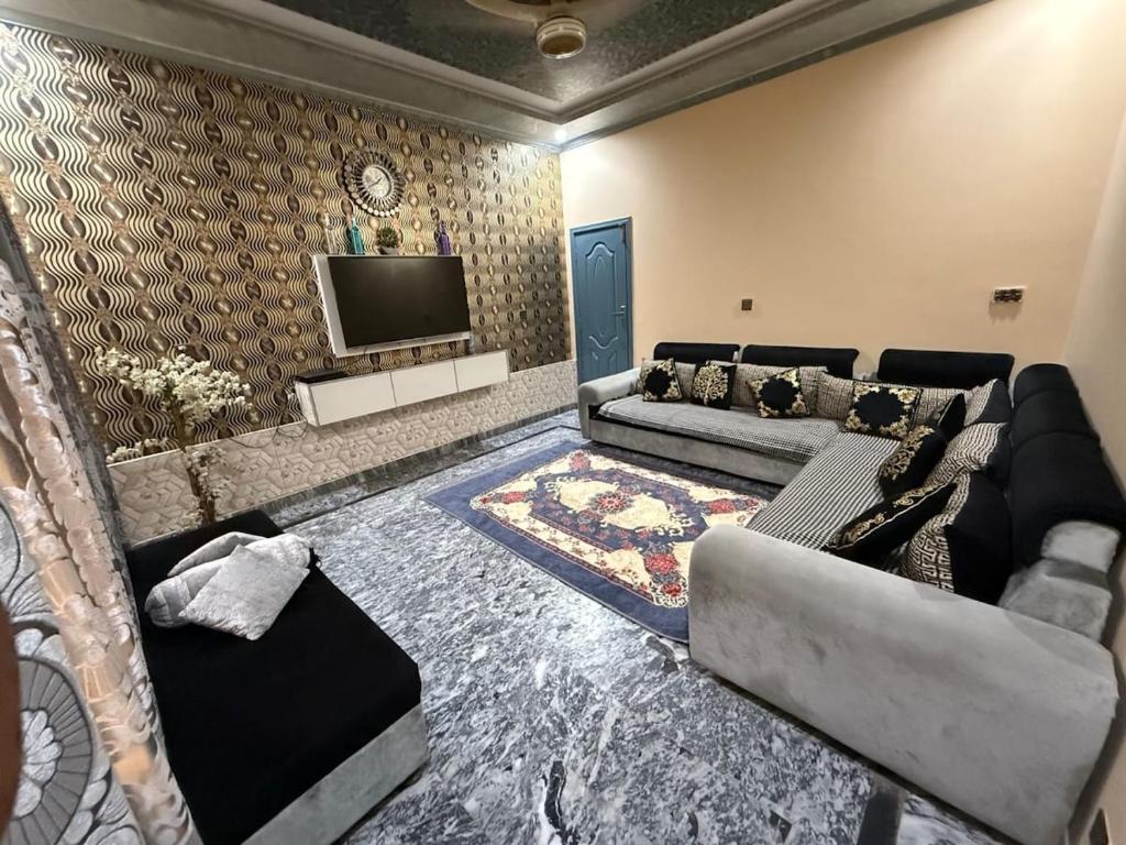 a living room with a couch and a tv at UK Guest House in Chāh Mahūnwāla
