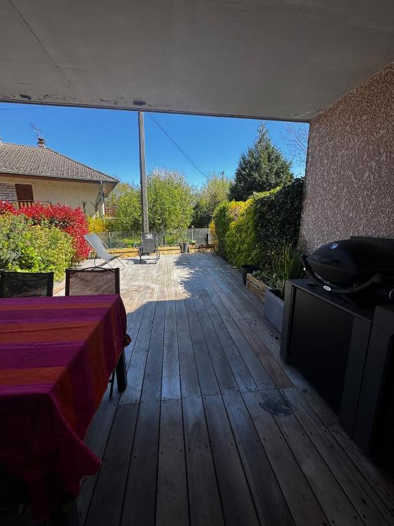 a wooden deck with a table and a tv on it at Charmant pied à terre entre lac et montagne in Bourdeau