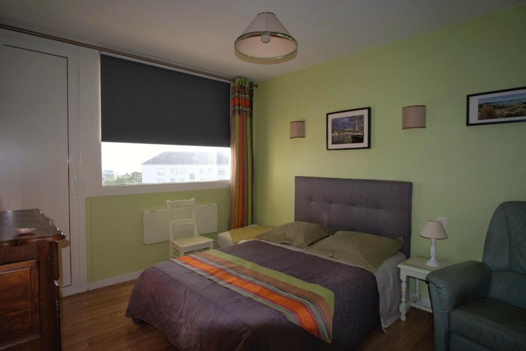 a bedroom with a bed and a window and a chair at La chouette verte in Granville