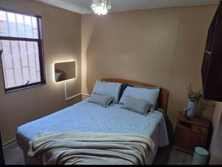 a bedroom with a bed with blue sheets and a window at Habitaciones Express Calama in Calama