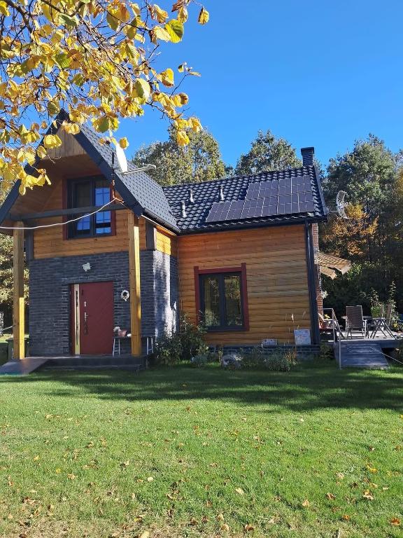 a house with a red door and a yard at Chata Nova in Milejczyce