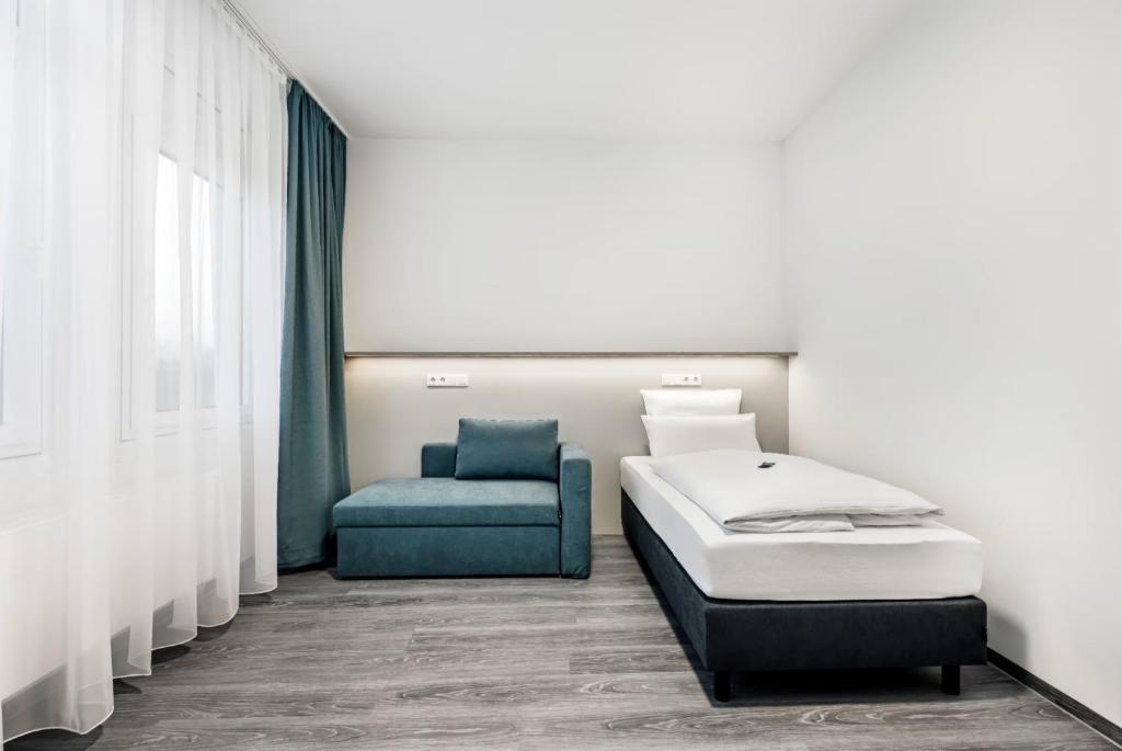 a bedroom with a bed and a blue chair at Oskar25 Aparthotel in Ismaning