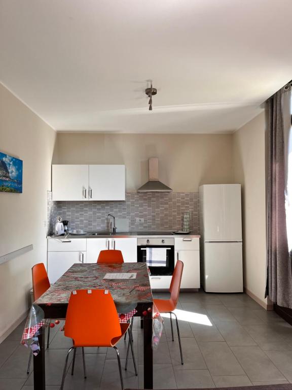 a kitchen with a dining table and orange chairs at El Jardin in Bellano