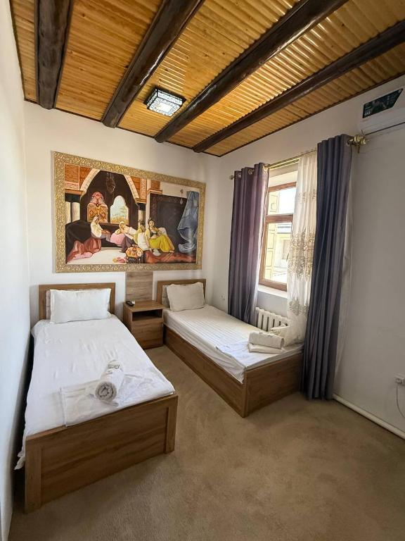 a bedroom with two beds and a painting on the wall at Guest house Afsona old city in Bukhara