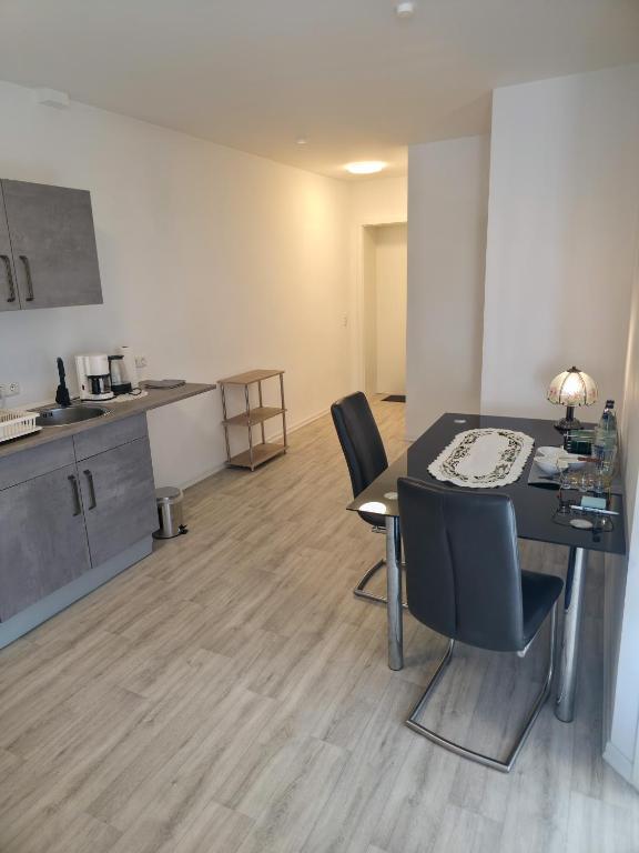 a room with a table and chairs and a kitchen at Weserblick Apartment Stolzenau 24h Selfcheckin in Stolzenau
