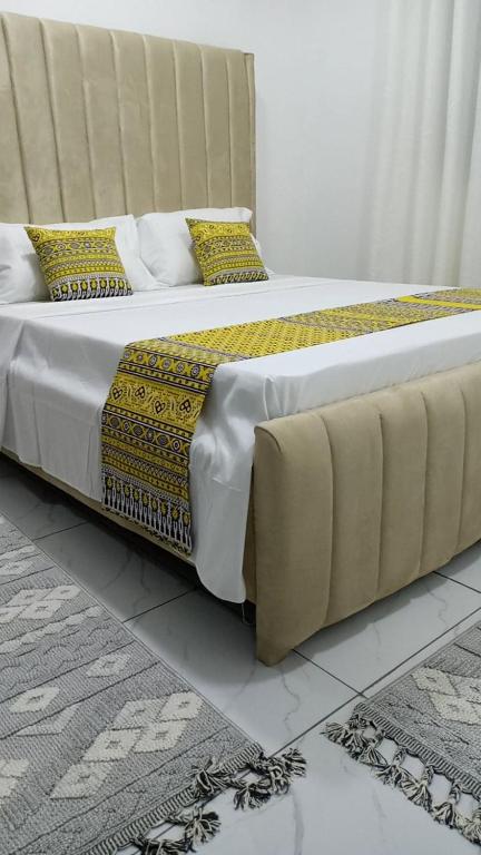 a large bed with yellow and black pillows on it at Jojos Serenity Stay in Bamburi