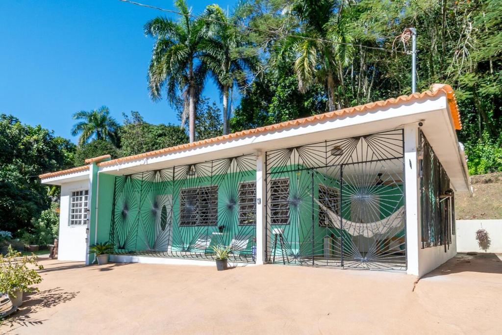 a green and white building with palm trees in the background at Comfortable & Spacious Mountain Home in Utuado in Cayuco