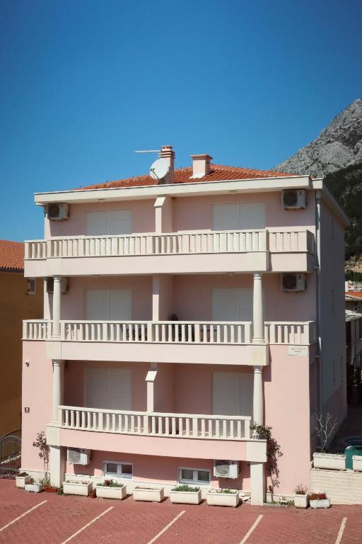 a large pink building with a large balcony at Apartmani Podest II in Baška Voda