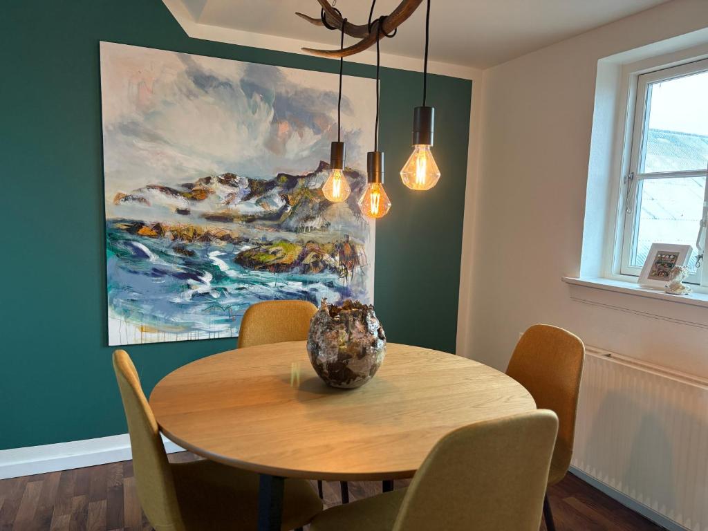 a dining room with a table and a painting at Art Apartment Sønderbygaard in Vinderup