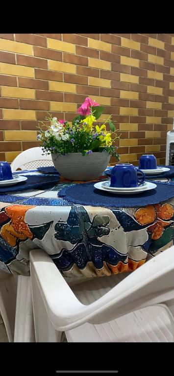 a table with two bowls and plates and flowers on it at House Duque de Caxias in Duque de Caxias