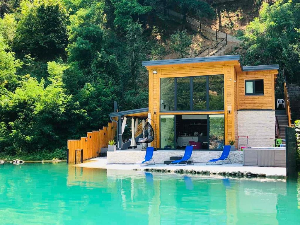 a tiny house on the water with blue chairs at Lake house Emerald in Jablanica