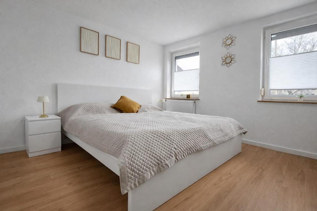a white bedroom with a bed and two windows at The Günz Homes 1 in Günzburg