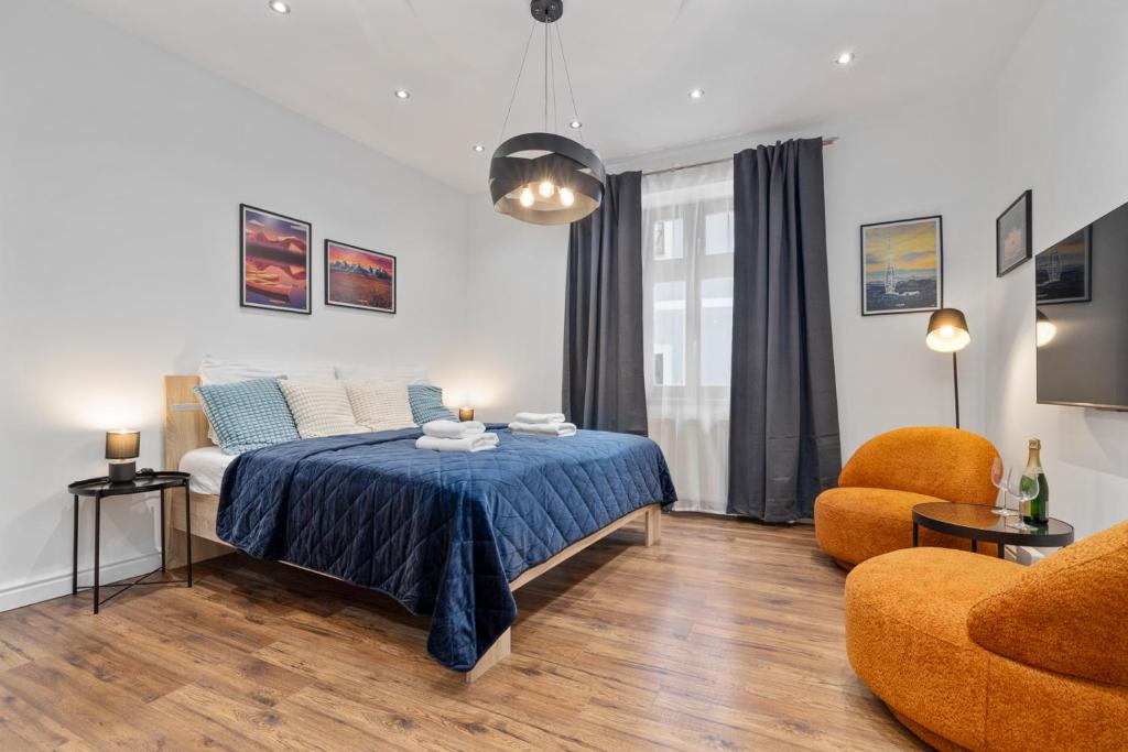 a bedroom with a bed with a blue blanket and a chair at Klariska Apartment near Michael's Gate in Bratislava
