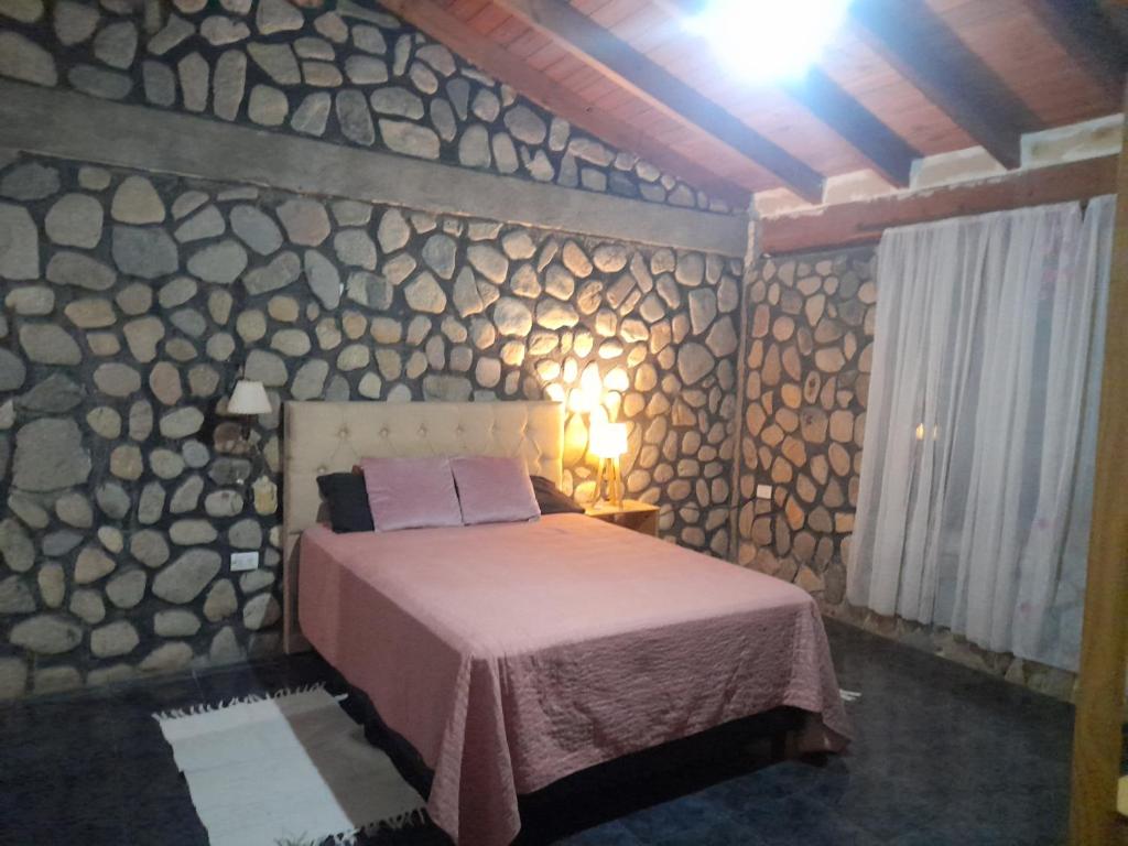 a bedroom with a bed and a stone wall at Casa El molinito in Chilecito