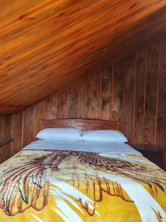 a bed in a room with a wooden wall at Las Bromelias in Coconuco