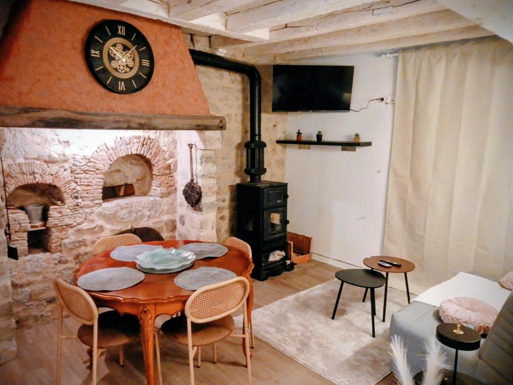 a living room with a table and a clock on the wall at Maisonnette Beauceronne in Eole-en-Beauce