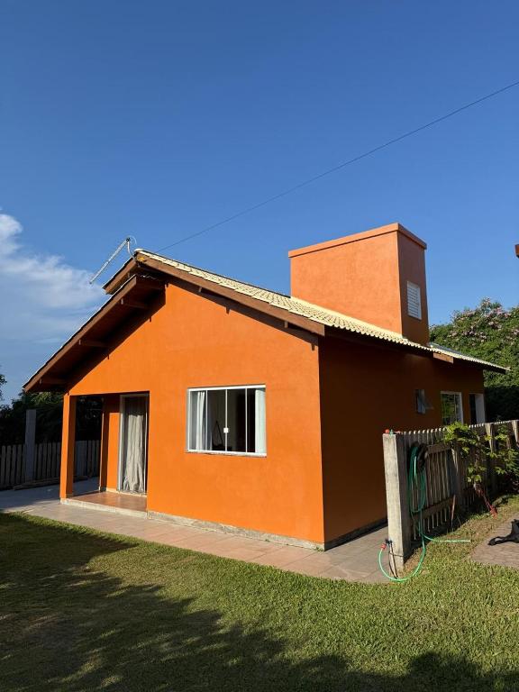a small orange house with a window in a yard at Riba House in Imbituba